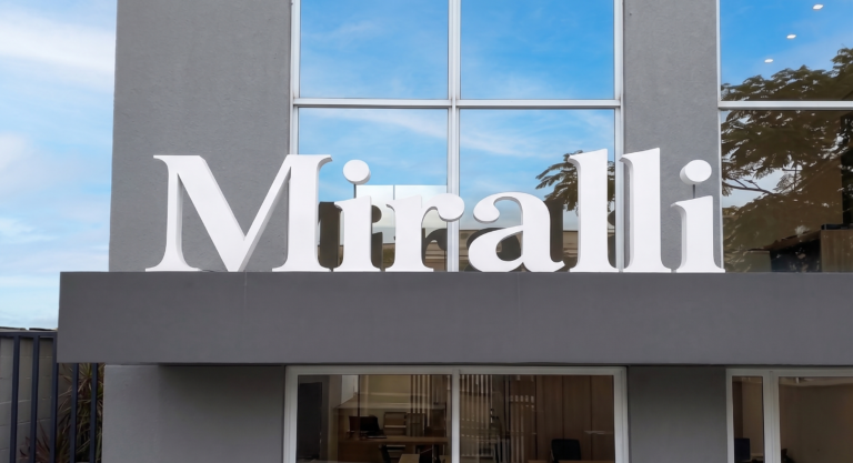 Fachada comercial moderna com logótipo em letra caixa branca 3D, instalada sobre marquise cinza. Projeto de comunicação visual exterior de alto padrão.
